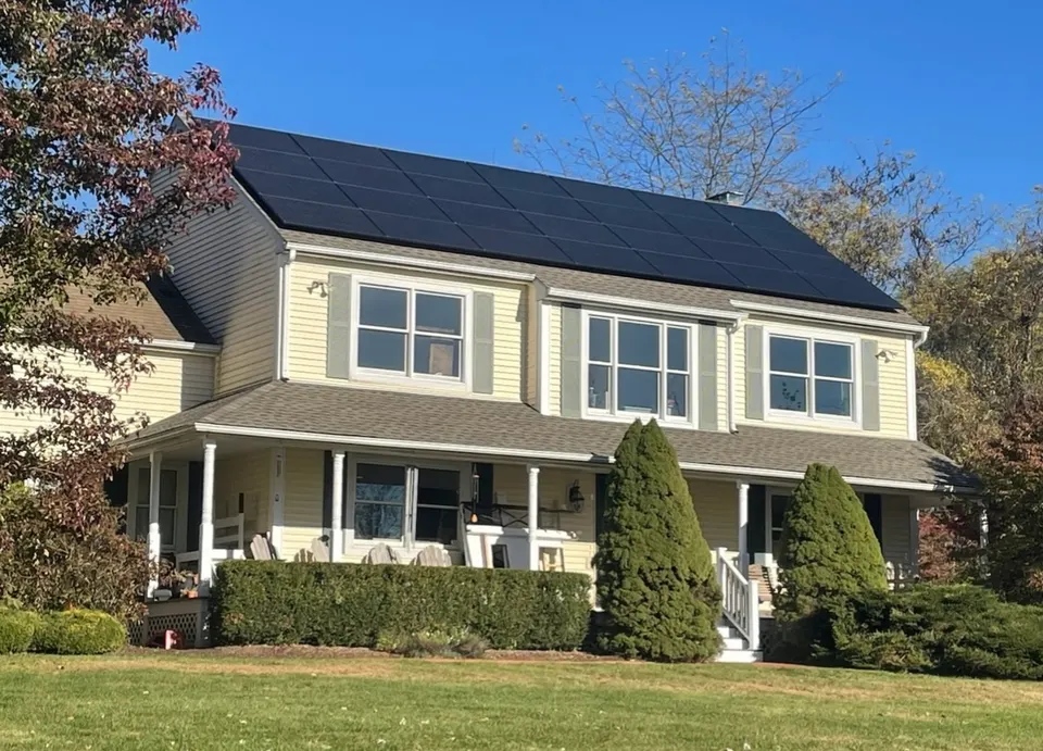 Finished black solar panels across the upper roof of a yellow residential home