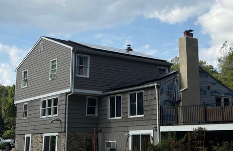 Solar panels on a home's roof, with an unfinished exterior section visible.